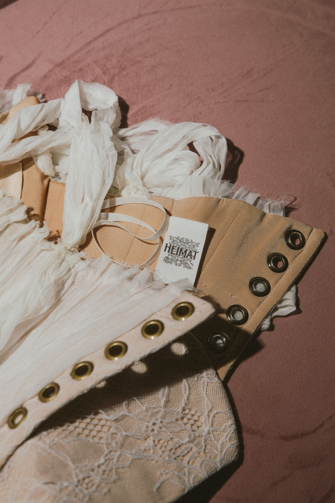 A Heimat label stitched inside a corset, beside raw-edged silk and lace